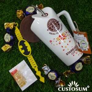 Alternative view of Batman Rakhi with Starbucks Mug of Chocolates loaded with Vanilla. Tilak Chandan Chawal Mishri pack